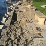 A retaining seawall is being repaired next to a body of water.