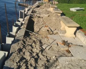 A retaining seawall is being repaired next to a body of water.