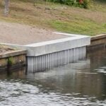A concrete retaining seawall on the side of a waterway.