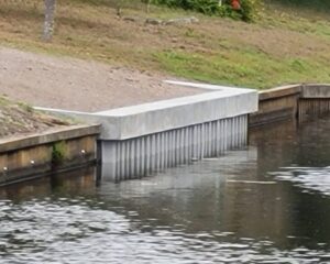 A concrete retaining seawall on the side of a waterway.