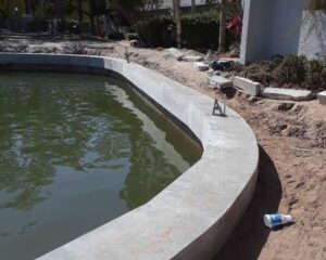 A concrete seawall is being built in front of a house.
