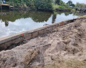 A retaining seawall is being repaired next to a river.