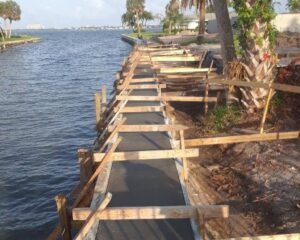 A concrete walkway and seawall is being built next to a body of water.