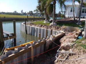 A dock and seawall is being built in the water near a house.