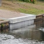 A waterway with a new concrete seawall installed in the side of the bank.