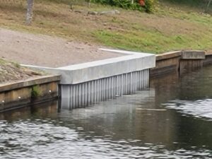 A waterway with a new concrete seawall installed in the side of the bank.