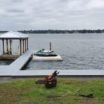 A new custom boat dock installation on a lake with palm trees and a boat.