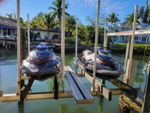 Two jet skis parked on a new custom dock in front of a house.
