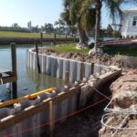 A seawall is being built in the water near a house.