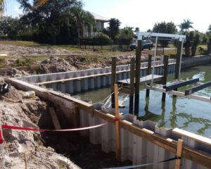 A seawall is being built in the water near a house.