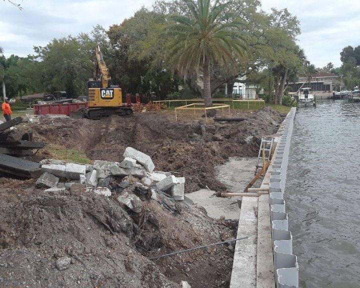 A construction crew is working on the side of a body of water.