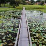 A bridge over a pond with lily pads.