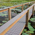 A wooden bridge over a pond full of water lilies.